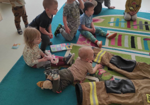 Zdjęcie dzieci siedzących na dywanie podczas zajęć z okazji Dnia Strażaka.