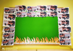 Zdjęcie tablicy grupy Pszczółki z ułożonymi i przyklejonymi na białe kartki w formacie A4 strażackimi puzzlami z obrazkami wozów strażackich.