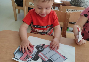 Zdjęcie Stanisława próbującego ułożyć swoje puzzle przedstawiające obrazek wozu strażackiego.