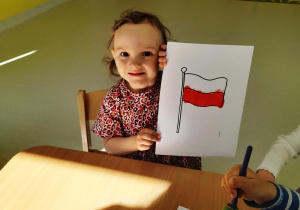 Zdjęcie Neli prezentującej swoją flagę Polski.
