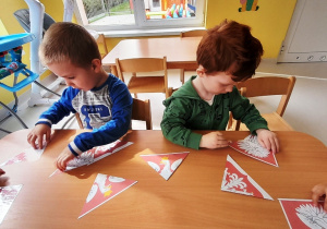 Dorian i Aleksander w skupieniu układają z puzzli omawiany symbol narodowy.