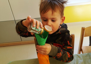 Tymon wsypuje kolorową posypkę do swojej butelki.