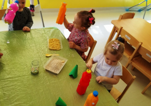 Dzieci przy stole wykonujące butelkowe grzechotki.