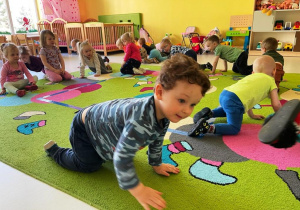 Dzieci czworakują po dywanie podczas zabawy ruchowej.