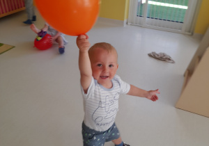Adam z pomarańczowym balonem w dłoni.