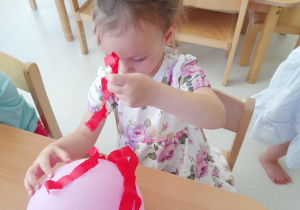 Zdjęcie Neli przyklejającej bibułowe włosy na balonik.