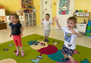 Troje dzieci tańczących na dywanie.