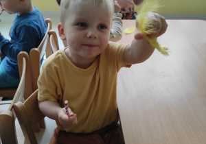 Henryk pokazuje opiekunce robiącej zdjęcie żółte piórko.