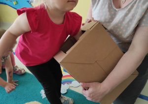 Skupiona Hanna próbuje wylosować ukrytą zabawkę w pudełku.