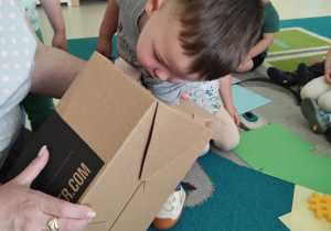 Szymon poszukuje w pudełku ukryte przedmioty.
