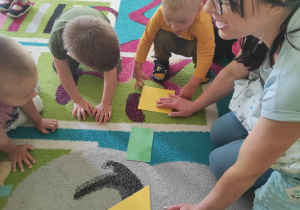 Dzieci razem z opiekunką oglądają na dywanie pozostałe trzy figury.