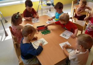 Dzieci z grupy Biedroneczki siedzące przy stole podczas pracy plastycznej.