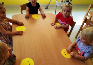Dzieci z grupy Biedroneczki siedzące przy stole w czasie wykonywania pracy plastycznej.