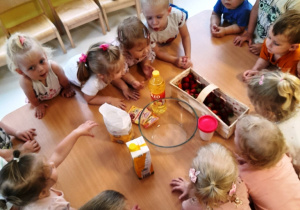 Dzieci z grupy Biedroneczki przy wspólnym stole z produktami do zrobienia babeczek.