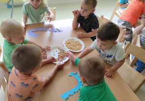 Zdjęcie dzieci ozdabiających płatkami kukurydzianymi rączki ośmiornicy.