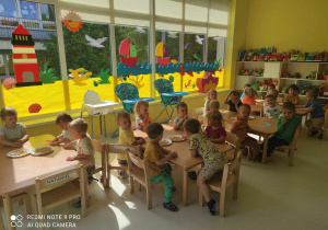 Zdjęcie dzieci z grupy Pszczółki siedzących przy stoliczku przed wykonywaniem pracy plastycznej pt. ,,OŚMIORNICA IDZIE DO SALONU PIĘKNOŚCI''.