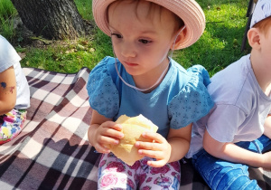 Nela zajada bułeczkę na małym pikniku podczas wycieczki.
