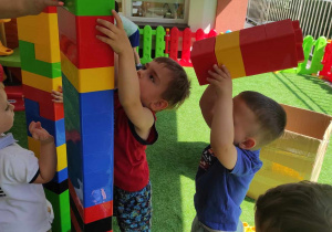 Nataniel i Szymon wspólnie budują wysoką kolorową wieżę.