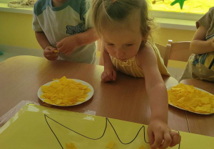 Zdjęcie Lilianny przyklejającej na słoneczko żółtą bibułę.