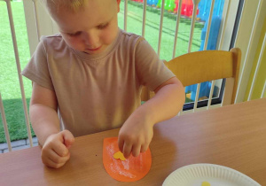 Marcel przykleja na swój pomarańczowy lód żółte serduszko.