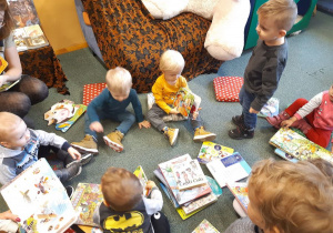 Zdjęcie dzieci siedzących na dywanie z książkami.