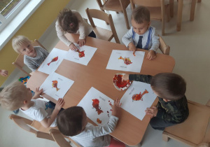 Maluchy przy stolikach malują farbami ptaszki.