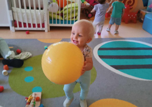 Zdjęcie Tobiasza z dużą gumową żółtą piłką.