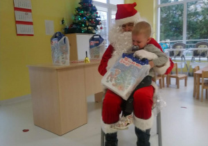 Mikołaj z prezentem na kolanach u Świętego Mikołaja