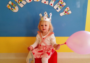 Urodzinowe zdjęcie dziewczynki z dyplomem i balonikiem.