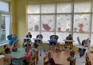 Dzieci z grupy Biedroneczki siedzące przy stole przed rozpoczęciem pracy plastycznej.