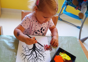 Lila maluje za pomocą pędzla i kolorowych farb folię bąbelkową.