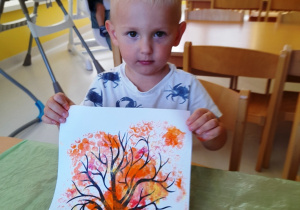 Adam prezentuje zrobione przez siebie kolorowe drzewko.