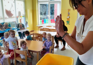 Opiekunka pokazuje dzieciom ,jak myć ręce.