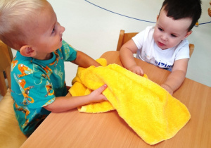 Maluchy dotykają miękki, żółty ręcznik.