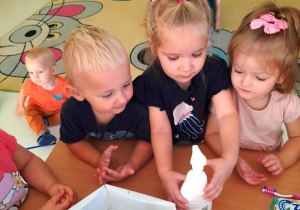 Kilkoro dzieci z grupy Biedroneczki przygląda się produktom służącym do dbania o higienę.