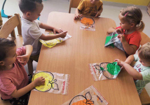 Zdjęcie dzieci rozsmarowujących farby w strunowych foliówkach.
