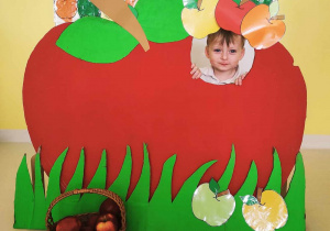 Maksymilian pozuje do zdjęcia w czerwonym tekturowym jabłuszku podczas Światowego Dnia Jabłka.