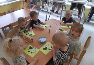 Zdjęcie dzieci przy stoliku podczas pracy plastycznej.