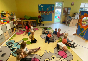 Dzieci siedzące na dywanie podczas opowiadania wiersza w formie teatrzyku.