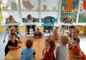 Dzieci z grupy Biedroneczki zebrane przy wspólnym stole przed rozpoczęciem zajęć kulinarnych.