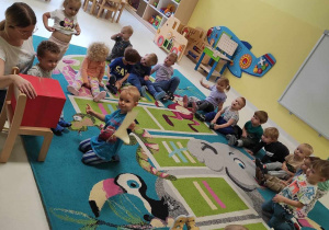 Zdjęcie dzieci siedzących na dywanie przygotowujących się do zajęć pt. ,,CZERWONA SKRZYNKA POCZTOWA''.