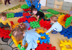 Zdjęcie dzieci bawiących się na dywanie kolorowymi klockami.
