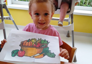 Kornelia pozuje do zdjęcia ze swoją układanką przedstawiającą kosz z warzywami.