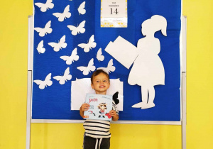 Zdjęcie uśmiechniętego Stanisława z książeczką na tle przepięknej niebieskiej ścianki.