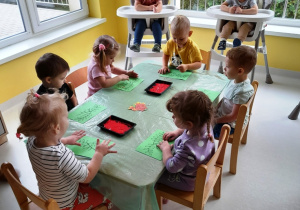 Maluchy z grupy Biedroneczki siedzące przy stole podczas pracy plastycznej.