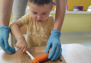 Szymon próbuje pokroić ugotowaną marchewkę.