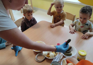 Opiekunka pokazuje dzieciom kiszonego ogóka.