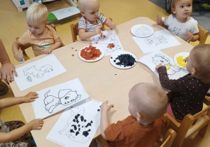 Zdjęcie dzieci ozdabiających kolorowymi kawałkami bibuł wydrukowane szablony kundelków.