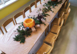 Zdjęcie złączonych stolików w grupie Pszczółki z przygotowanymi materiałami do pracy florystycznej pt. ,,JESIENNE WAZONY Z DYNI''.