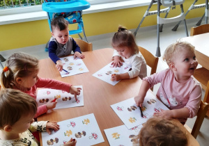 Dzieci z grupy Biedroneczki siedzące przy stole podczas zajęć dydaktycznych.